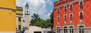 Historic Clock Tower in Tirana, Albania, surrounded by colorful architecture and a bright summer sky.