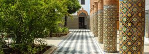 Intricate mosaic columns and peaceful courtyard garden at Dar el Bacha Palace in Marrakech, Morocco.