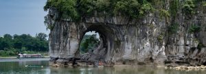Elephant Trunk Hill natural rock arch over Li River in Guilin China with boat passing through scenic landscape