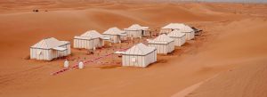 Luxury desert camp with traditional white tents surrounded by sand dunes in M’Hamid, Morocco