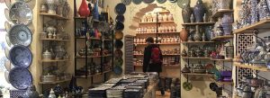 Traditional blue Moroccan ceramic pottery and decorative plates displayed inside an artisan shop in Fez, Morocco.