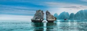 Fighting Cock Islet limestone rock formations rising from emerald waters in Halong Bay, Vietnam