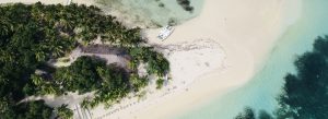 Aerial view of tropical Fiji island beach with palm trees, white sand, clear turquoise water, and anchored boat