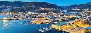 Aerial evening view of Flekkefjord harbor town surrounded by mountains and fjords in Norway.