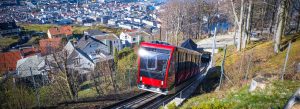 Red funicular railway climbing a hillside with panoramic city views in Bergen Norway