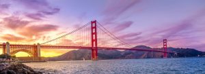 Golden Gate Bridge at sunset in San Francisco with colorful skies, ocean waters, and surrounding California hills.
