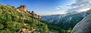 Panoramic landscape view of the Guadarrama Mountains in Spain with rocky peaks, pine forests, and scenic valleys.