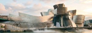 Modern exterior view of the Guggenheim Museum Bilbao in Spain with its iconic titanium architecture beside the riverfront.