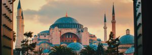 Front view of Hagia Sophia in Istanbul, Turkey, featuring its grand dome and towering minarets at sunset.
