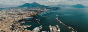 Aerial view of Naples Harbor in Italy with cruise ships, the Bay of Naples, and Mount Vesuvius in the background.