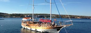Traditional gullet cruise boat sailing through the scenic Maltese harbour on a sunny day