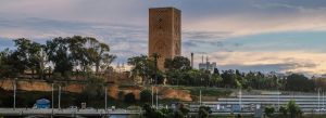 Hassan Tower in Rabat, Morocco surrounded by palm trees and cityscape at sunset.