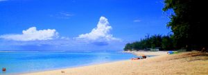 Sunny beach scene at Hermitage Lagoon in Reunion Island with crystal-clear turquoise water, white sand, and tropical coastal scenery.