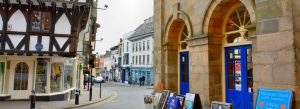 Historic timber-framed buildings and stone arches lining a street in Ludlow town centre, Shropshire, England.