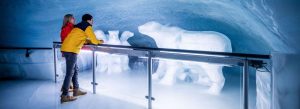 Visitors exploring the Ice Palace at Jungfraujoch Top of Europe surrounded by intricate ice sculptures inside a glacier in Switzerland.