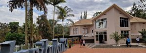 Visitors arriving at the Kigali Genocide Memorial in Rwanda surrounded by palm trees and modern memorial buildings.