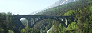 Historic Kylling Bridge crossing a lush mountain valley in Norway during summer.
