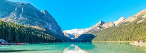 Turquoise waters of Lake Louise surrounded by towering Rocky Mountains and evergreen forests in Banff National Park, Canada.