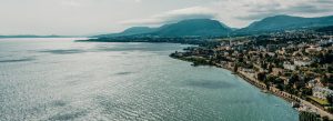Aerial view of Lake Neuchâtel in Switzerland with peaceful shoreline, mountains, and lakeside town.
