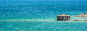 Beautiful turquoise waters of Lake Sevan in Armenia with a small lakeside structure surrounded by scenic mountain views.