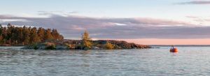 Sunset view over the rocky islands and calm waters of Lake Vänern in Sweden surrounded by pine forests.