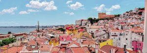 Colorful rooftops and historic buildings overlooking the waterfront in Lisbon, Portugal, on a bright sunny day.