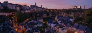 Evening panoramic view of Luxembourg City skyline with illuminated historic buildings and fortifications