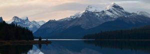 Snow-capped mountains reflected in the calm waters of Maligne Lake in Jasper National Park, Alberta