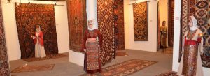 Traditional Armenian carpets displayed inside Megerian Carpet Museum in Yerevan, Armenia with women wearing authentic Armenian folk costumes.