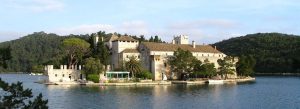 Monastery of St. Mary on a peaceful island in Croatia surrounded by calm blue water and lush green forests.