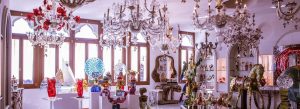Elegant handmade Murano glass chandeliers and colorful glass art displayed inside a Venetian glass factory.