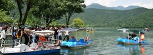 Visitors enjoying pedal boats at Nohur Lake surrounded by green mountains in Gabala, Azerbaijan