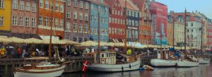 Colorful buildings and traditional wooden boats lining Nyhavn harbor in Copenhagen, Denmark.