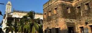 Historic buildings of Stone Town featuring the Old Fort and the House of Wonders surrounded by palm trees under a clear blue sky