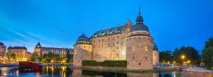 Illuminated Örebro Castle reflected in the river at dusk in Örebro, Sweden.