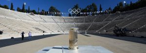 Panathenaic Stadium in Athens, Greece, with Olympic rings and historic marble seating under a clear blue sky.