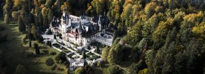 Aerial view of Peleş Castle surrounded by dense forest in the Carpathian Mountains near Sinaia, Romania.