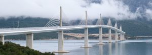 Modern Pelješac Bridge crossing the Adriatic Sea in Croatia with mountains and low clouds in the background.