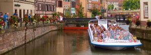 Tourist boat cruising through the canals of Petite France district in Strasbourg, France.