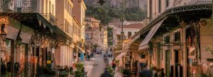 Plaka district street in Athens, Greece with traditional shops, neoclassical buildings, and scenic city views at sunset