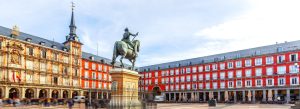 Historic Plaza Mayor square in Madrid, Spain with the equestrian statue of King Philip III and colorful traditional buildings.