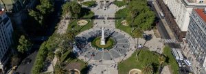 Aerial view of Plaza de Mayo in Buenos Aires, Argentina, featuring the central monument, palm trees, walking paths, and surrounding historic buildings.