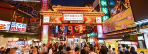 Crowded Raohe Street Night Market in Taipei Taiwan glowing with colorful lights and food stalls at night