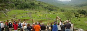 Visitors overlooking the scenic Ring of Kerry landscape in Ireland, with rolling green hills, stone walls, and mountain valleys in the background.