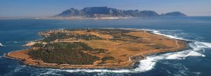 Aerial view of Robben Island in Table Bay, South Africa, with Table Mountain and the Cape Town coastline in the background.