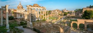 Ancient ruins of the Roman Forum with historic columns and temples in Rome, Italy under a clear blue sky