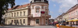 Historic city center of Sremska Mitrovica, Serbia, with elegant architecture, pedestrian streets, cafes, and festival banners.