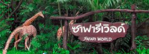 Entrance sign of Safari World in Bangkok surrounded by tropical greenery and giraffe sculptures.