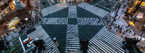 Aerial view of Shibuya Crossing in Tokyo, Japan, with hundreds of pedestrians crossing the famous multi-directional intersection at dusk.