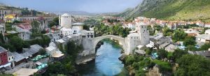 Historic Stari Most stone bridge over the Neretva River in Mostar, Bosnia and Herzegovina surrounded by traditional Balkan architecture.